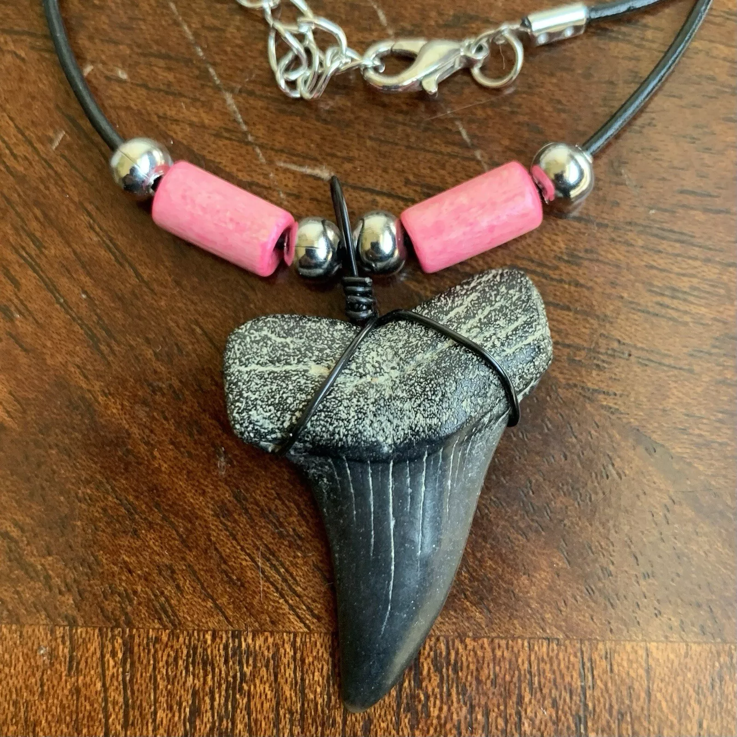 Real shark tooth necklace made from a fossil lesser white shark tooth pendant wrapped with black wire, hung on a black cotton cord with colorful beads