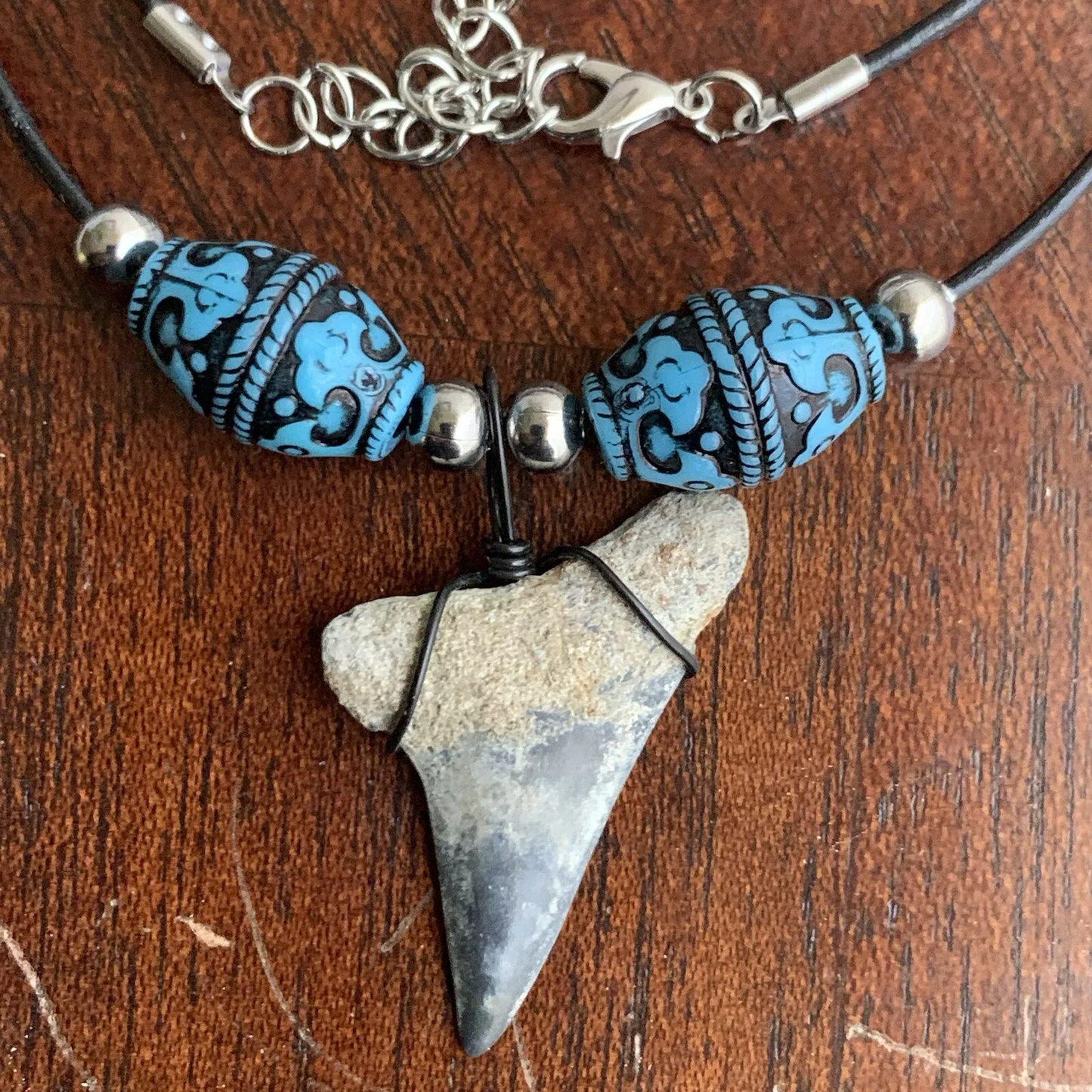 Real shark tooth necklace made from a fossil lesser white shark tooth pendant wrapped with black wire, hung on a black cotton cord with colorful beads