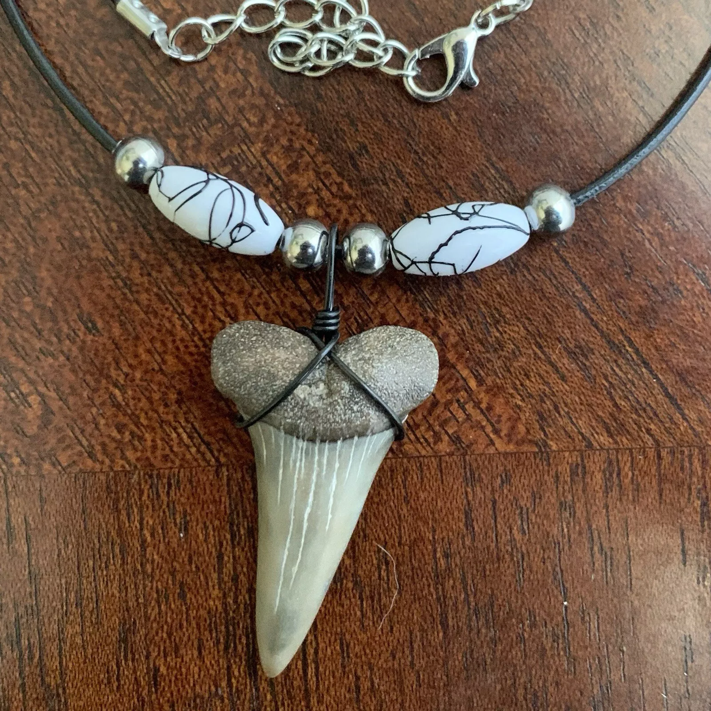 Real shark tooth necklace made from a fossil lesser white shark tooth pendant wrapped with black wire, hung on a black cotton cord with colorful beads