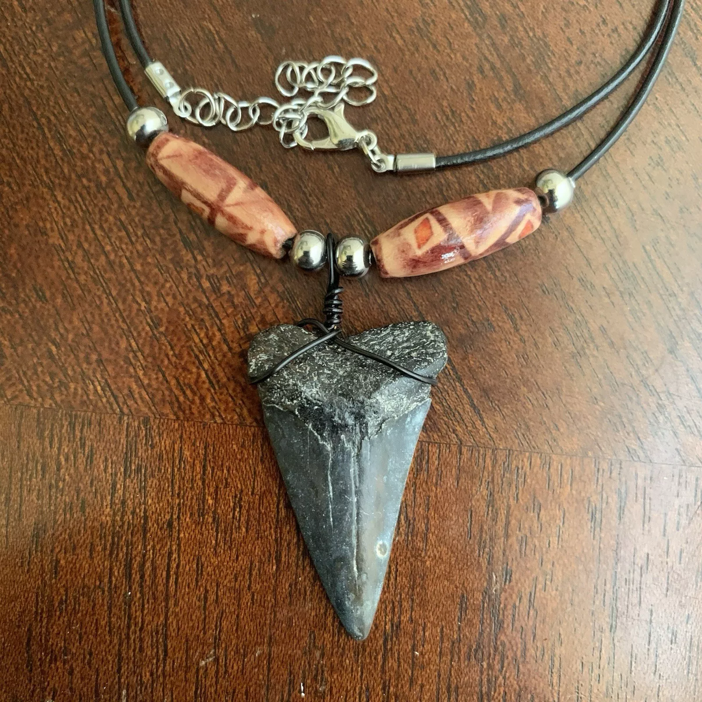 Real shark tooth necklace made from a fossil lesser white shark tooth pendant wrapped with black wire, hung on a black cotton cord with colorful beads