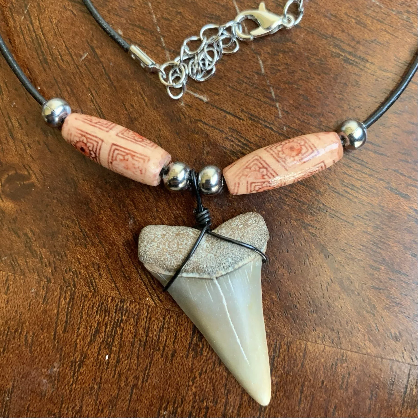 Real shark tooth necklace made from a fossil lesser white shark tooth pendant wrapped with black wire, hung on a black cotton cord with colorful beads
