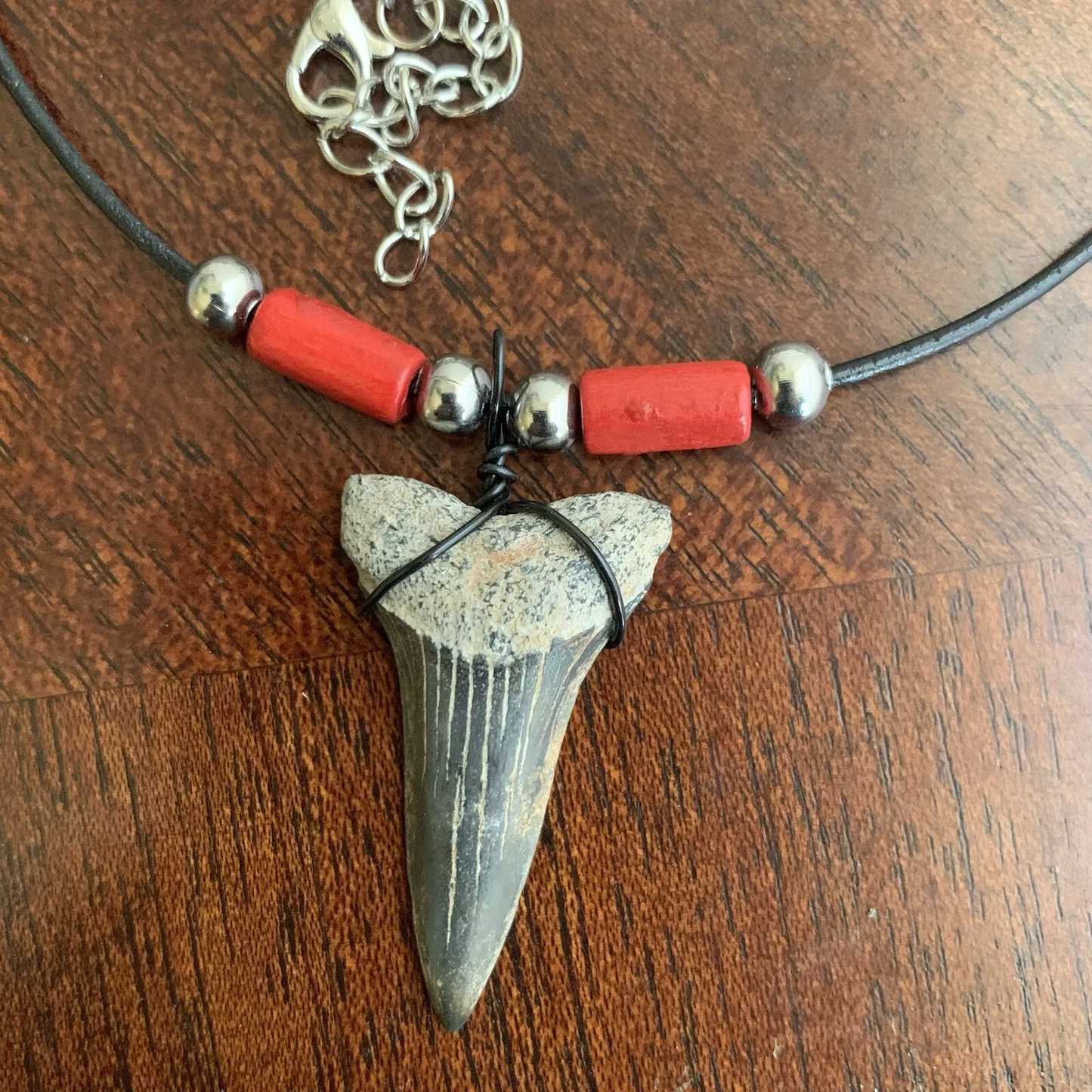 Real shark tooth necklace made from a fossil lesser white shark tooth pendant wrapped with black wire, hung on a black cotton cord with colorful beads