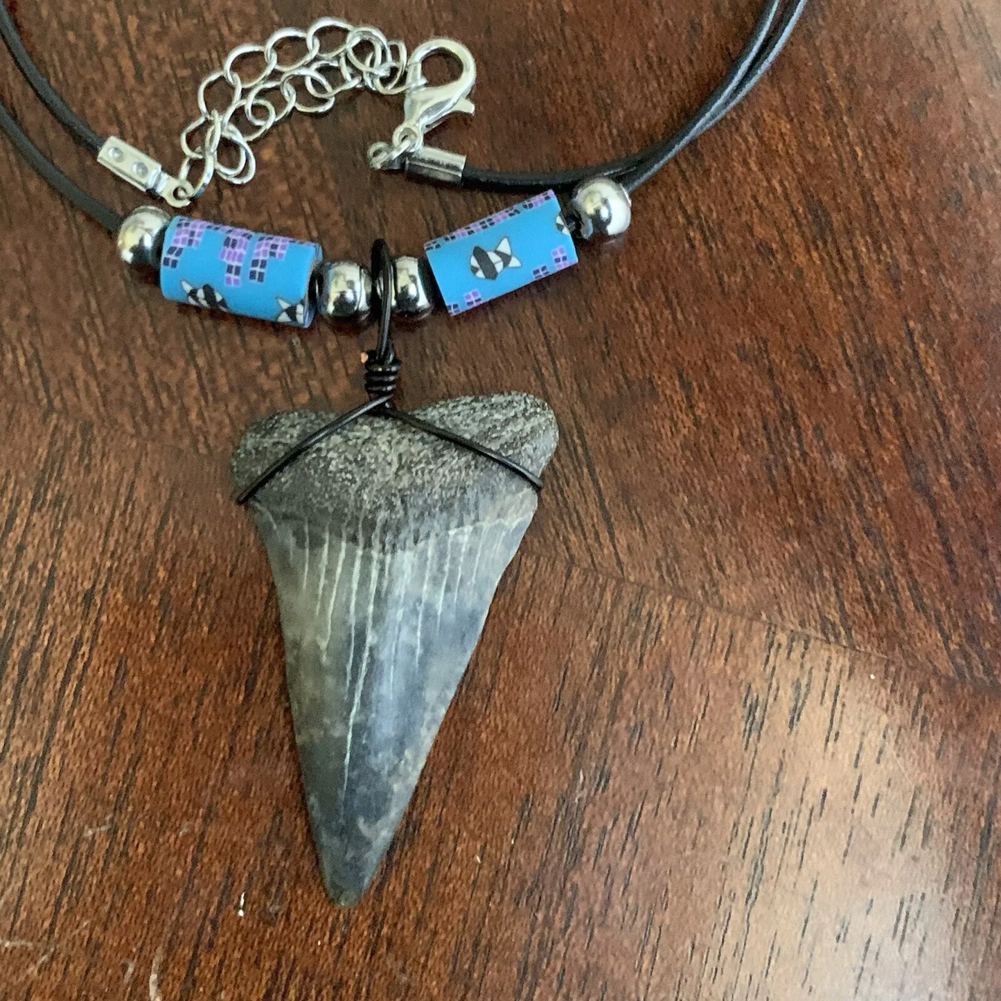 Real shark tooth necklace made from a fossil lesser white shark tooth pendant wrapped with black wire, hung on a black cotton cord with colorful beads