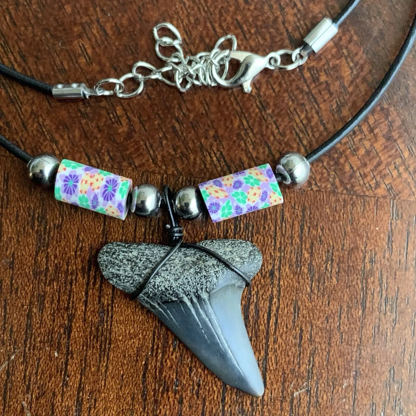 Real shark tooth necklace made from a fossil lesser white shark tooth pendant wrapped with black wire, hung on a black cotton cord with colorful beads