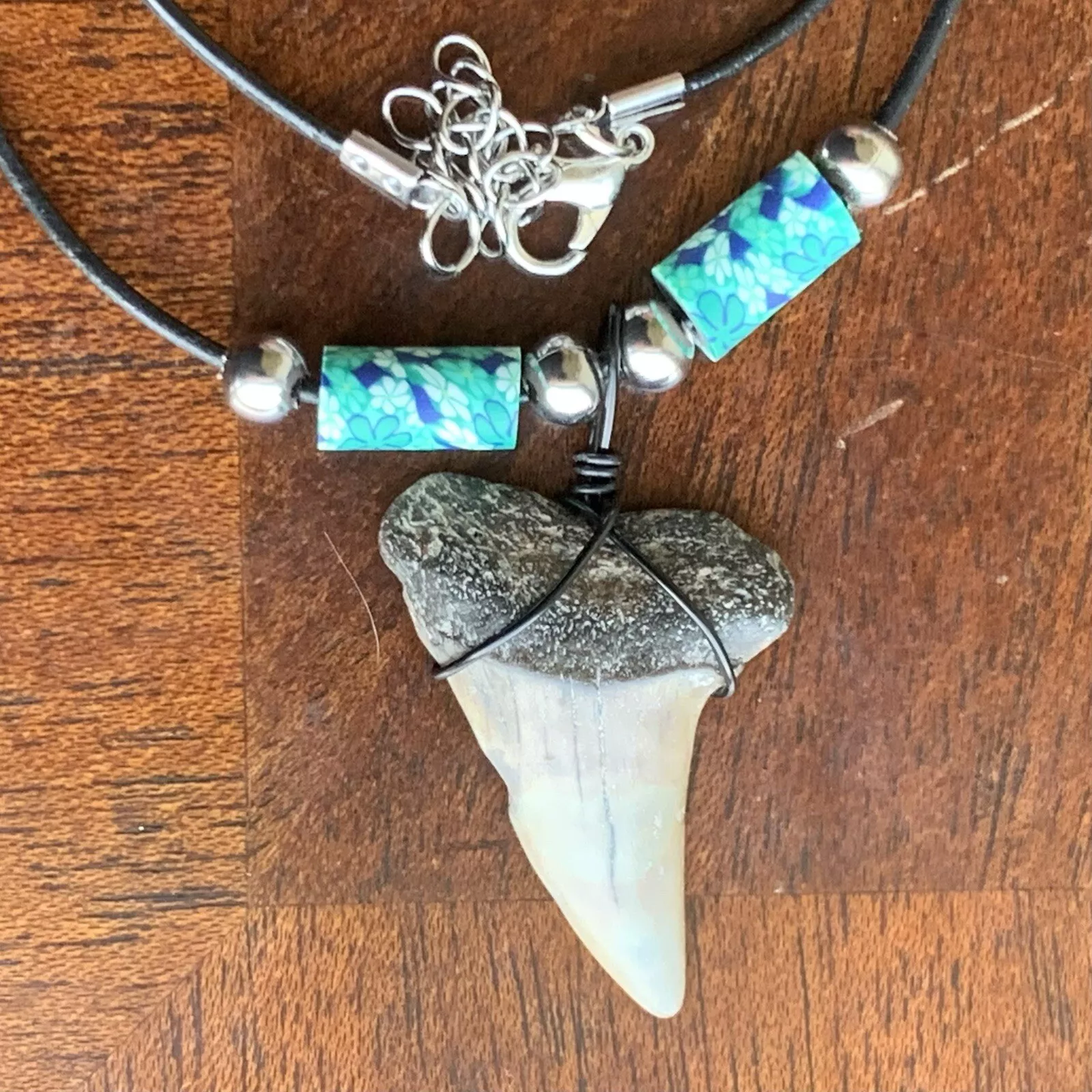Real shark tooth necklace made from a fossil lesser white shark tooth pendant wrapped with black wire, hung on a black cotton cord with colorful beads