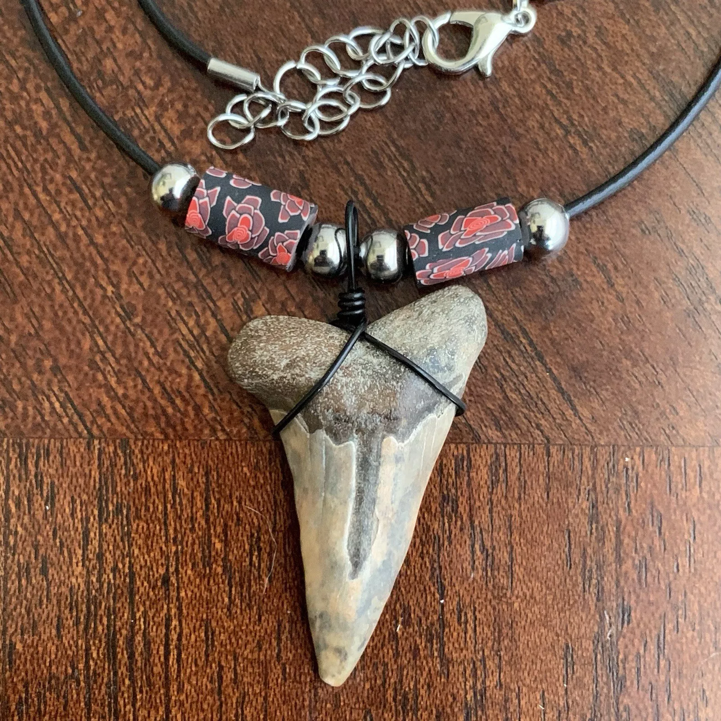 Real shark tooth necklace made from a fossil lesser white shark tooth pendant wrapped with black wire, hung on a black cotton cord with colorful beads