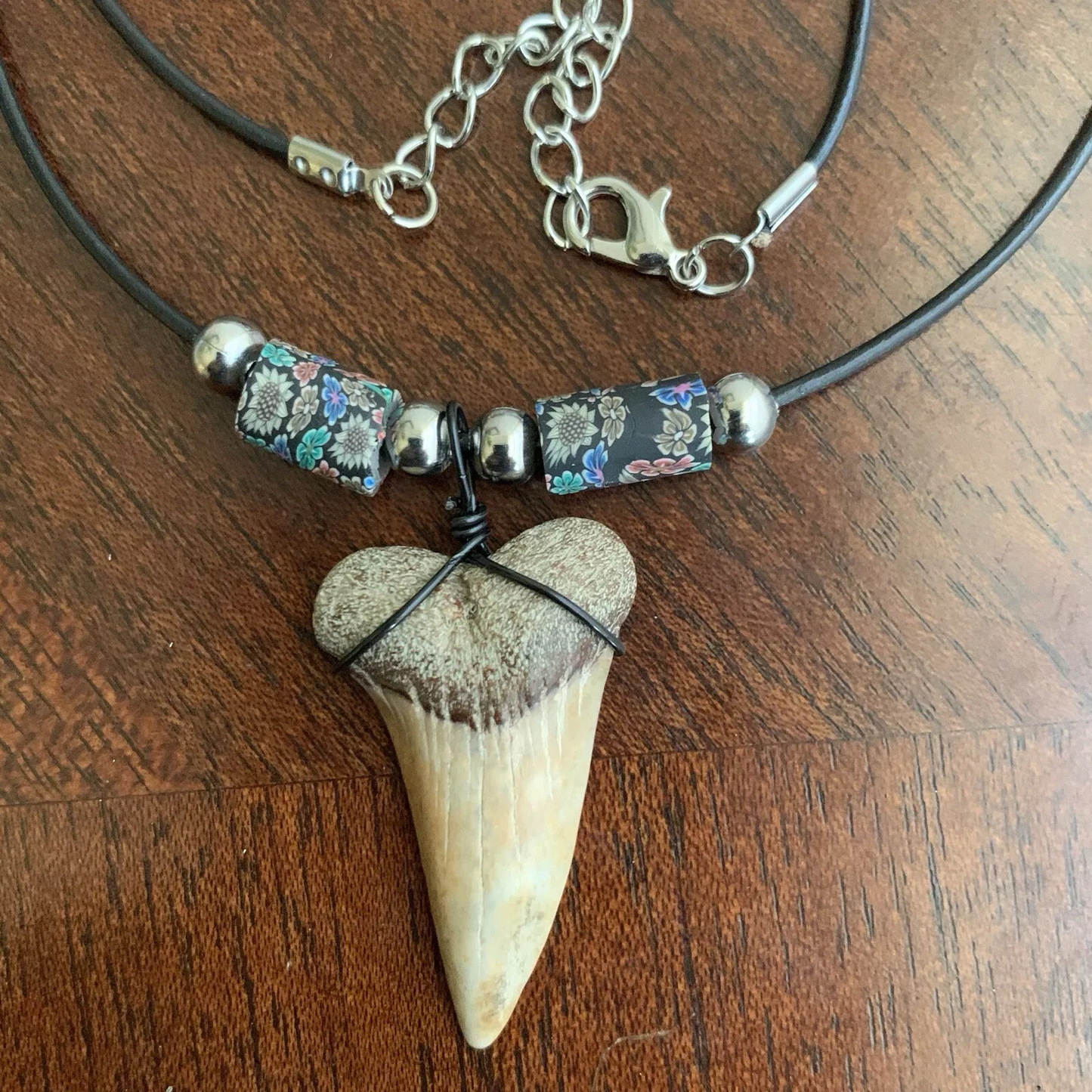 Real shark tooth necklace made from a fossil lesser white shark tooth pendant wrapped with black wire, hung on a black cotton cord with colorful beads