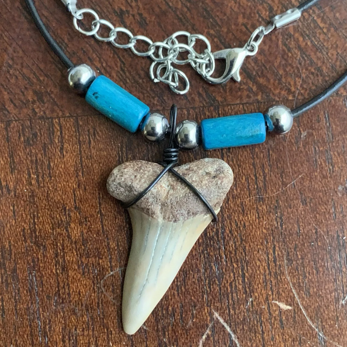 Real shark tooth necklace made from a fossil lesser white shark tooth pendant wrapped with black wire, hung on a black cotton cord with colorful beads