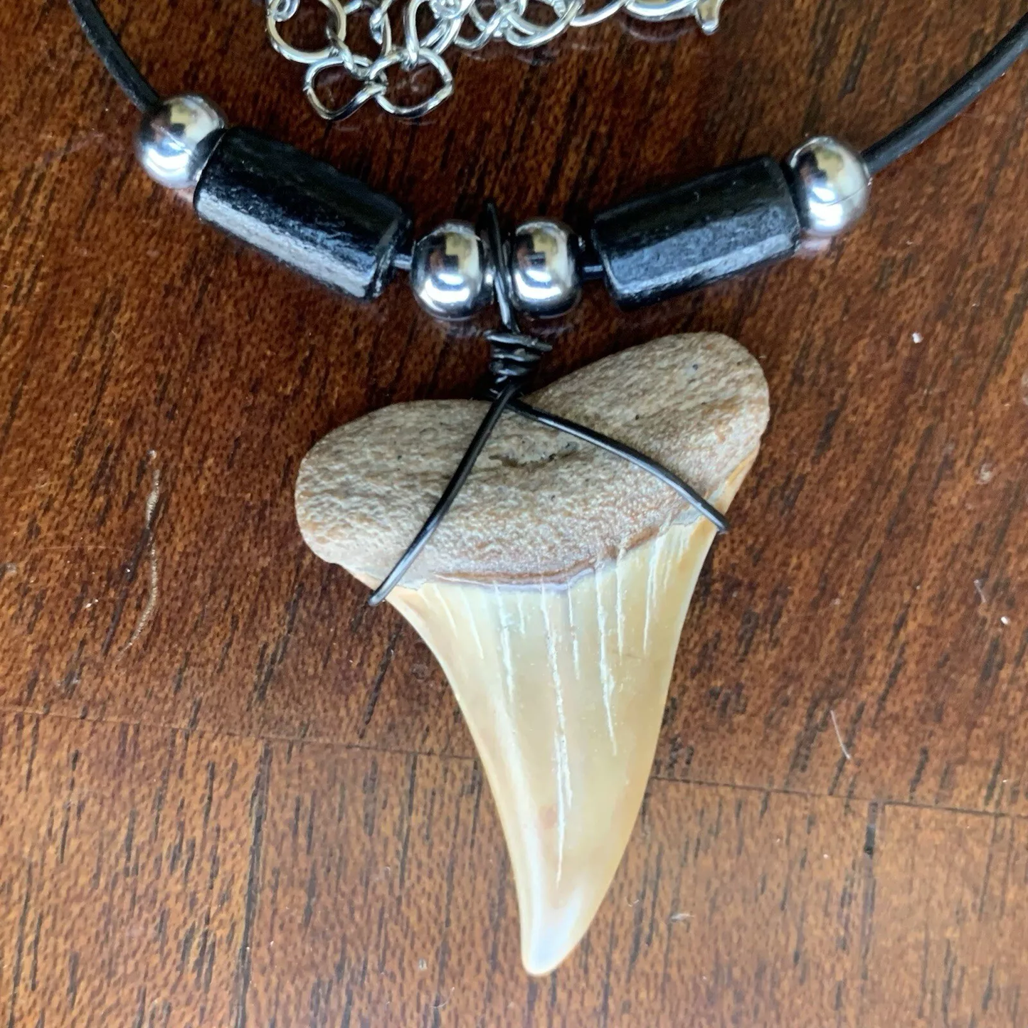 Real shark tooth necklace made from a fossil lesser white shark tooth pendant wrapped with black wire, hung on a black cotton cord with colorful beads
