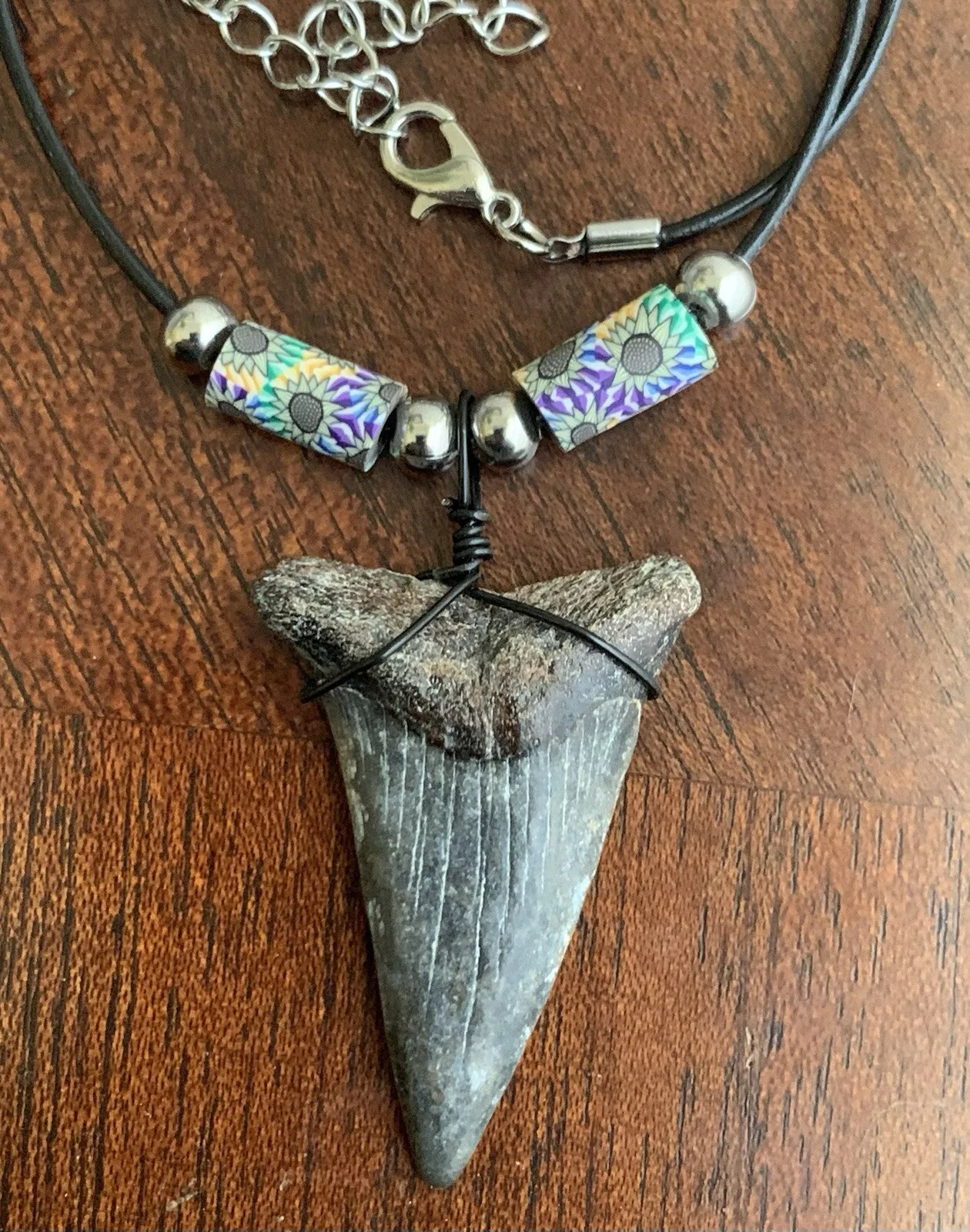 Real shark tooth necklace made from a fossil lesser white shark tooth pendant wrapped with black wire, hung on a black cotton cord with colorful beads