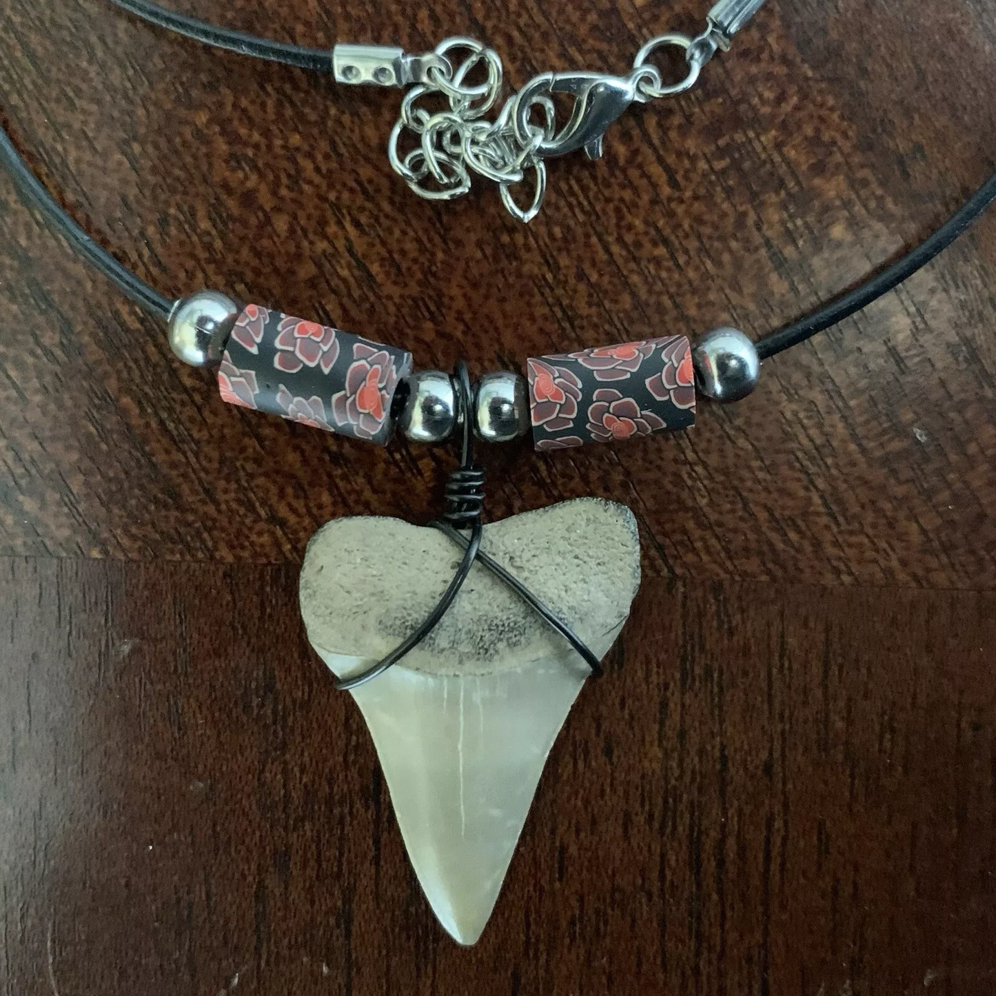 Real shark tooth necklace made from a fossil lesser white shark tooth pendant wrapped with black wire, hung on a black cotton cord with colorful beads