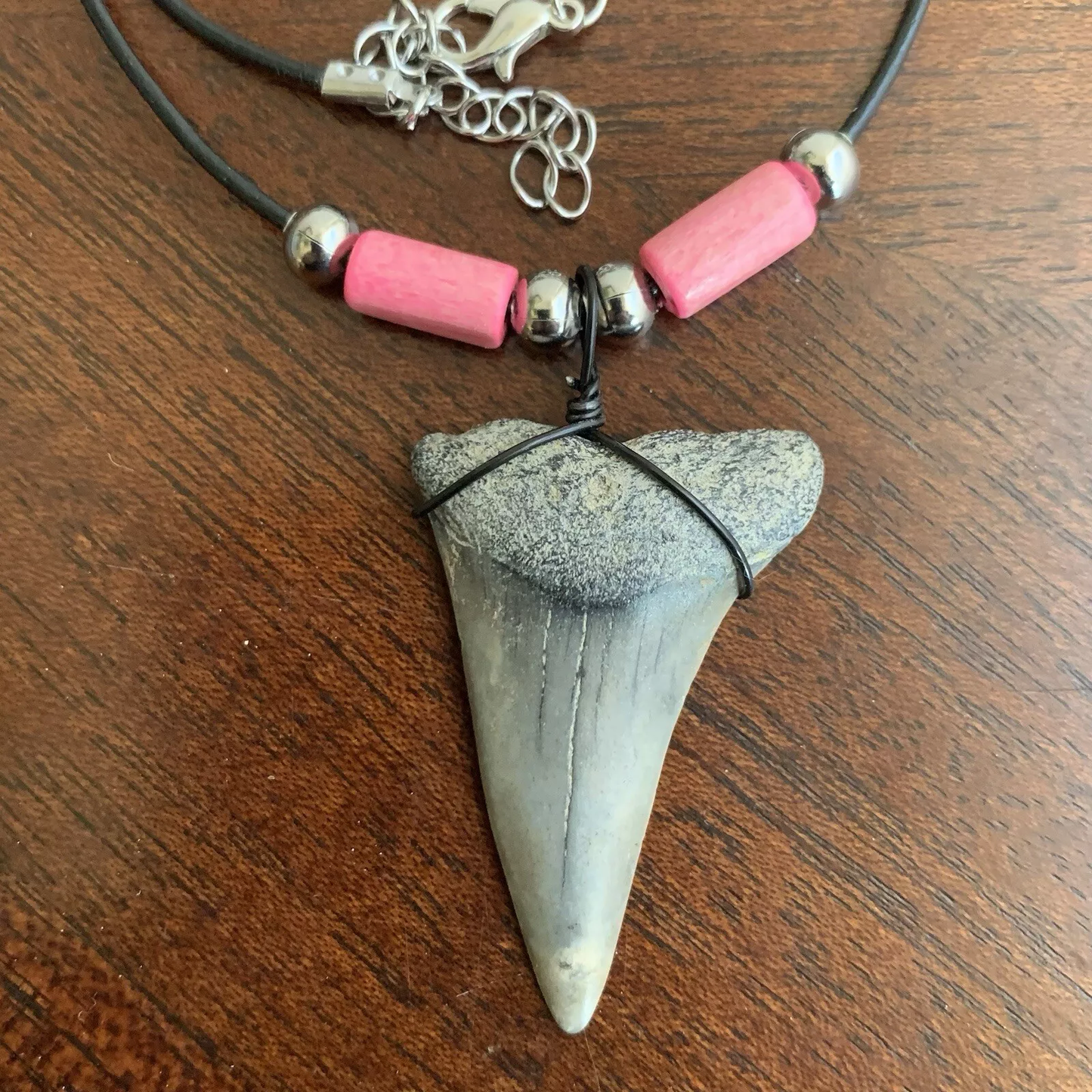 Real shark tooth necklace made from a fossil lesser white shark tooth pendant wrapped with black wire, hung on a black cotton cord with colorful beads