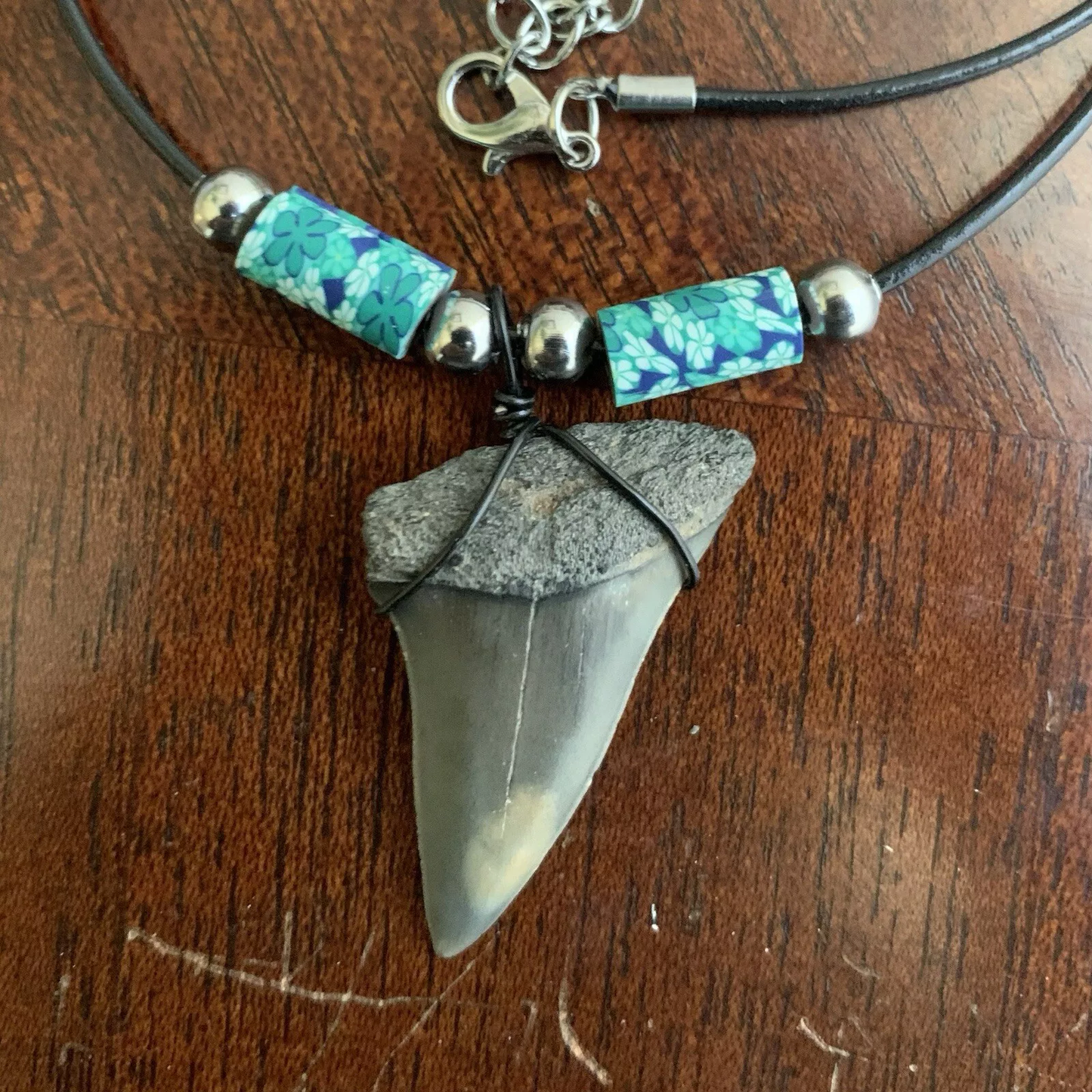 Real shark tooth necklace made from a fossil lesser white shark tooth pendant wrapped with black wire, hung on a black cotton cord with colorful beads