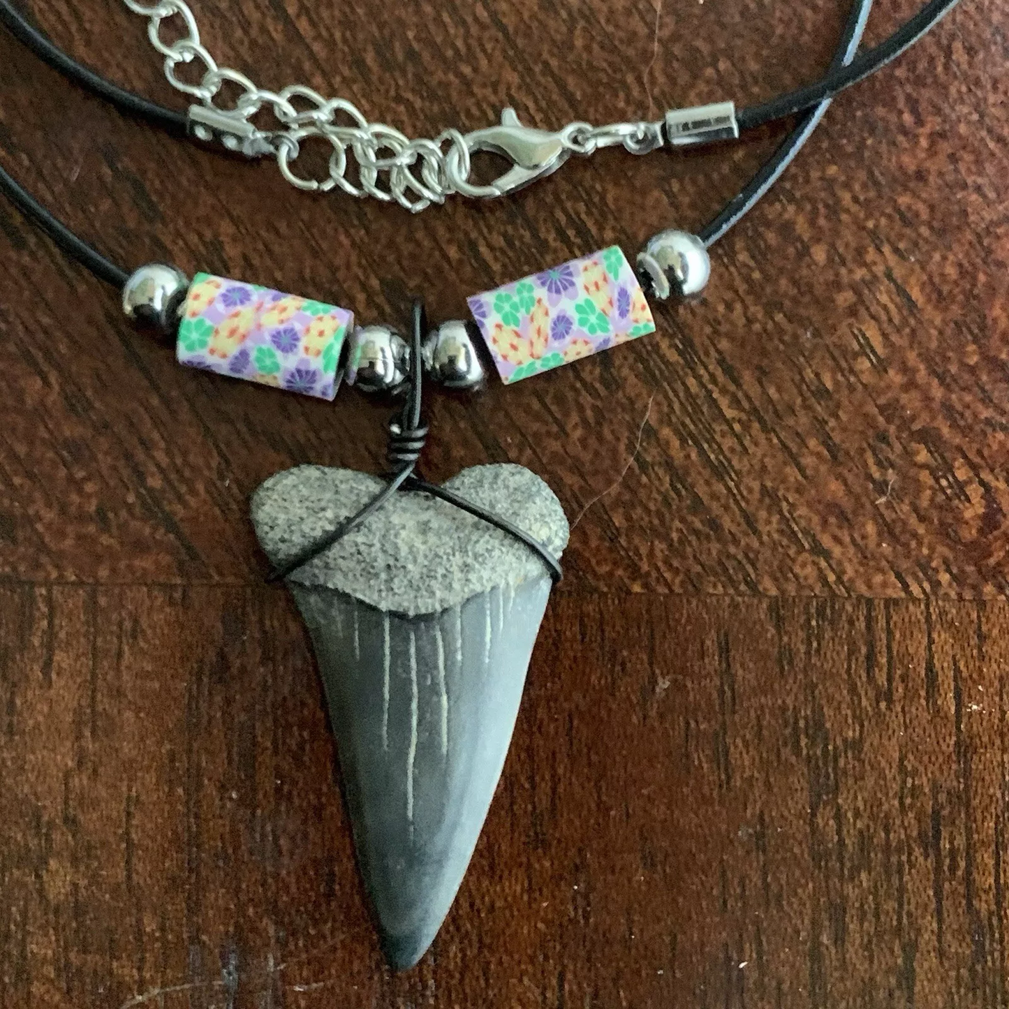 Real shark tooth necklace made from a fossil lesser white shark tooth pendant wrapped with black wire, hung on a black cotton cord with colorful beads