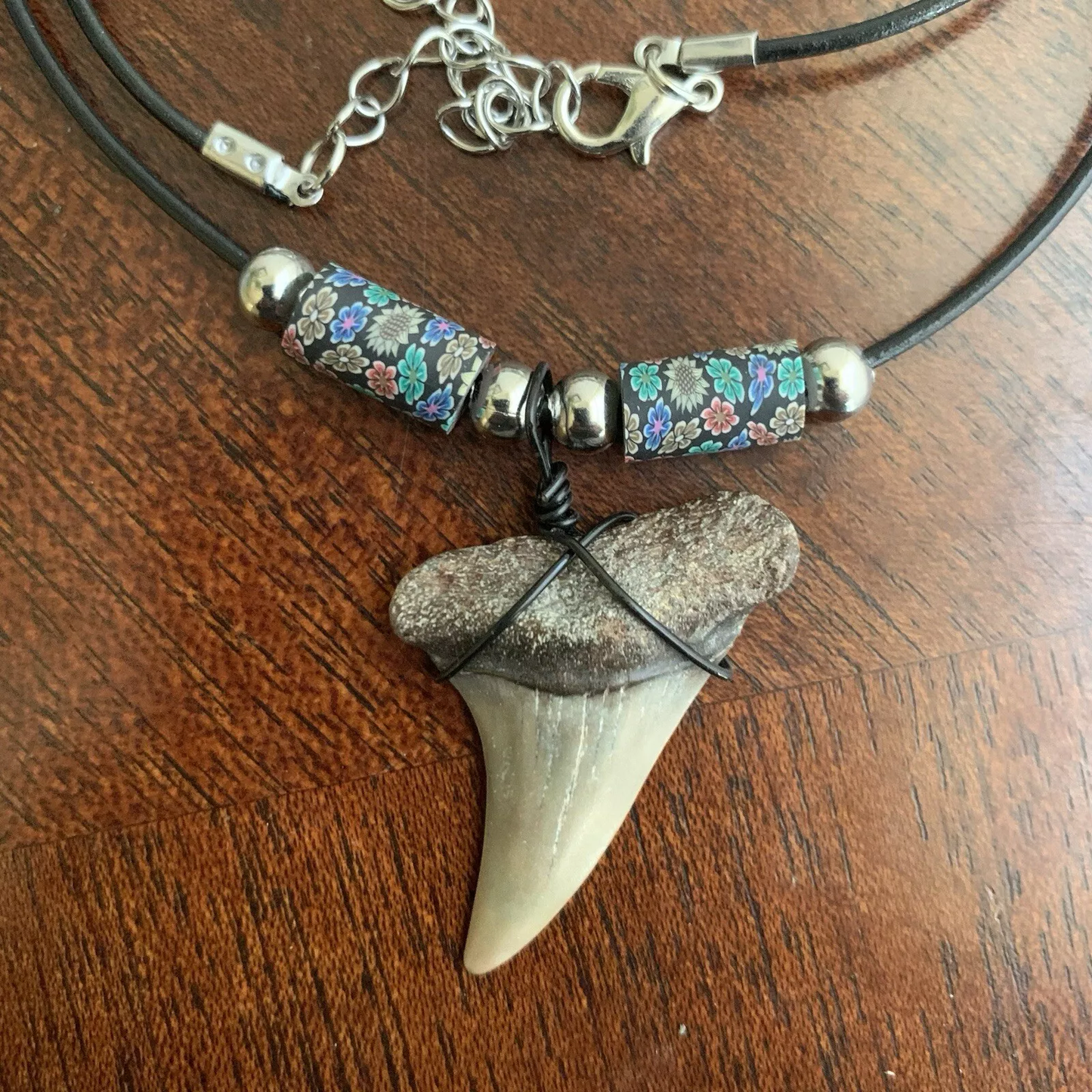 Real shark tooth necklace made from a fossil lesser white shark tooth pendant wrapped with black wire, hung on a black cotton cord with colorful beads
