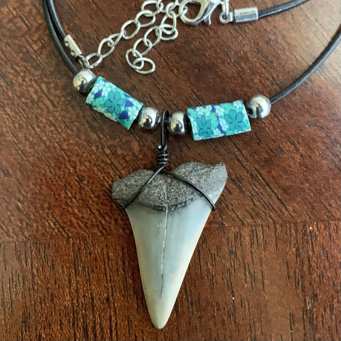 Real shark tooth necklace made from a fossil lesser white shark tooth pendant wrapped with black wire, hung on a black cotton cord with colorful beads