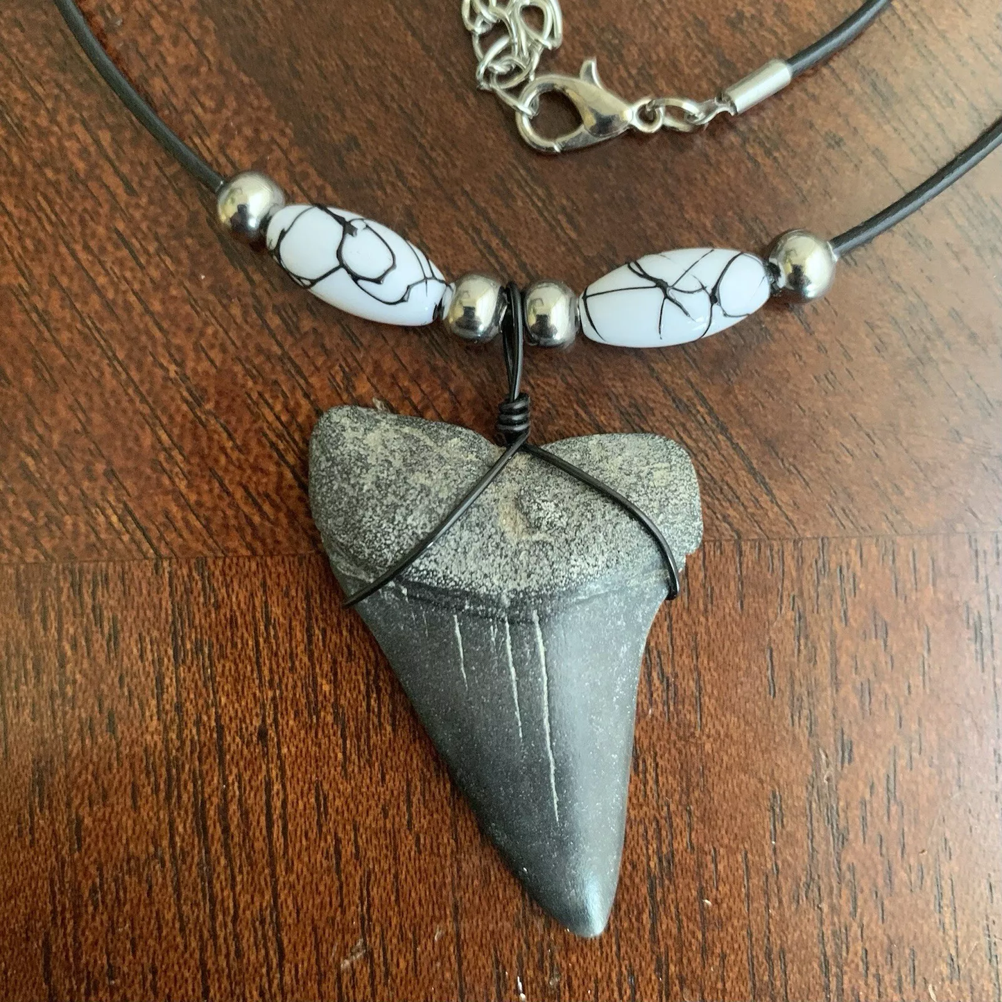 Real shark tooth necklace made from a fossil lesser white shark tooth pendant wrapped with black wire, hung on a black cotton cord with colorful beads