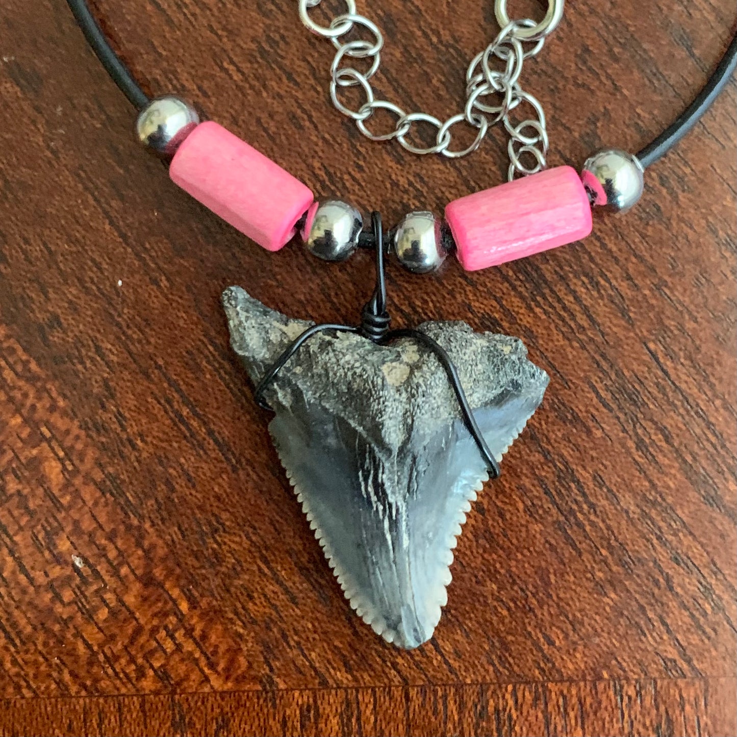 Real shark tooth necklace made from a fossil snaggle shark tooth pendant wrapped with black wire, hung on a black cotton cord with colorful beads