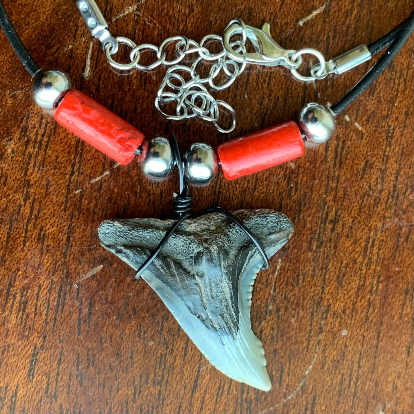 Real shark tooth necklace made from a fossil snaggle shark tooth pendant wrapped with black wire, hung on a black cotton cord with colorful beads