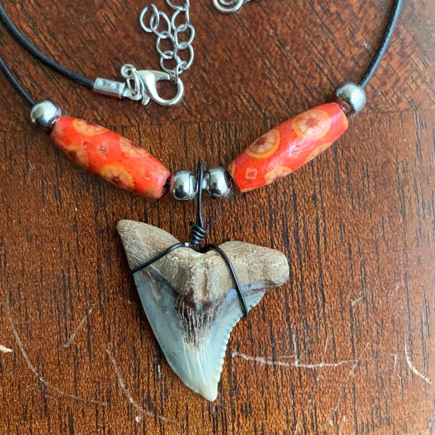 Real shark tooth necklace made from a fossil snaggle shark tooth pendant wrapped with black wire, hung on a black cotton cord with colorful beads