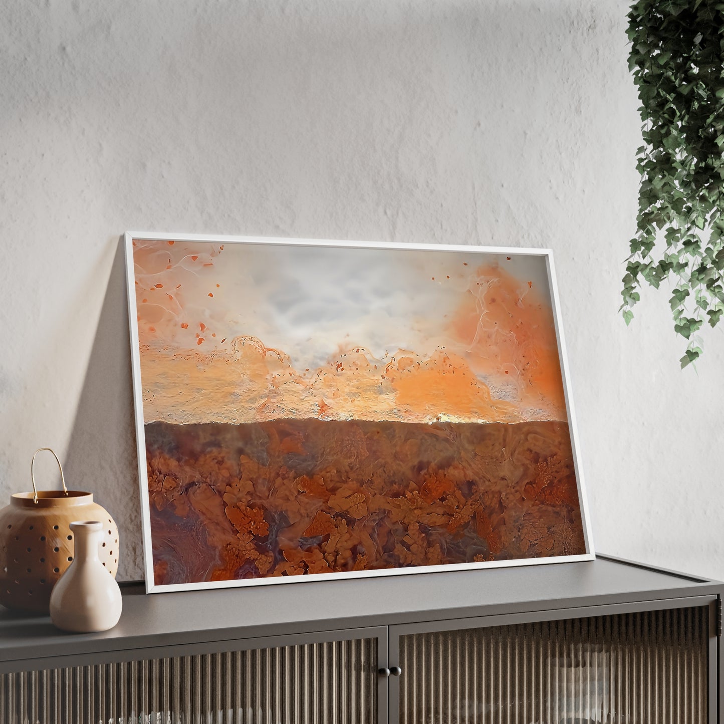 Wall art print capturing a captivating close-up photograph of a plume agate with its orange, white, and brown color . The picture is in a white frame and is leaning against the wall, on a low height cabinet, in the living room.