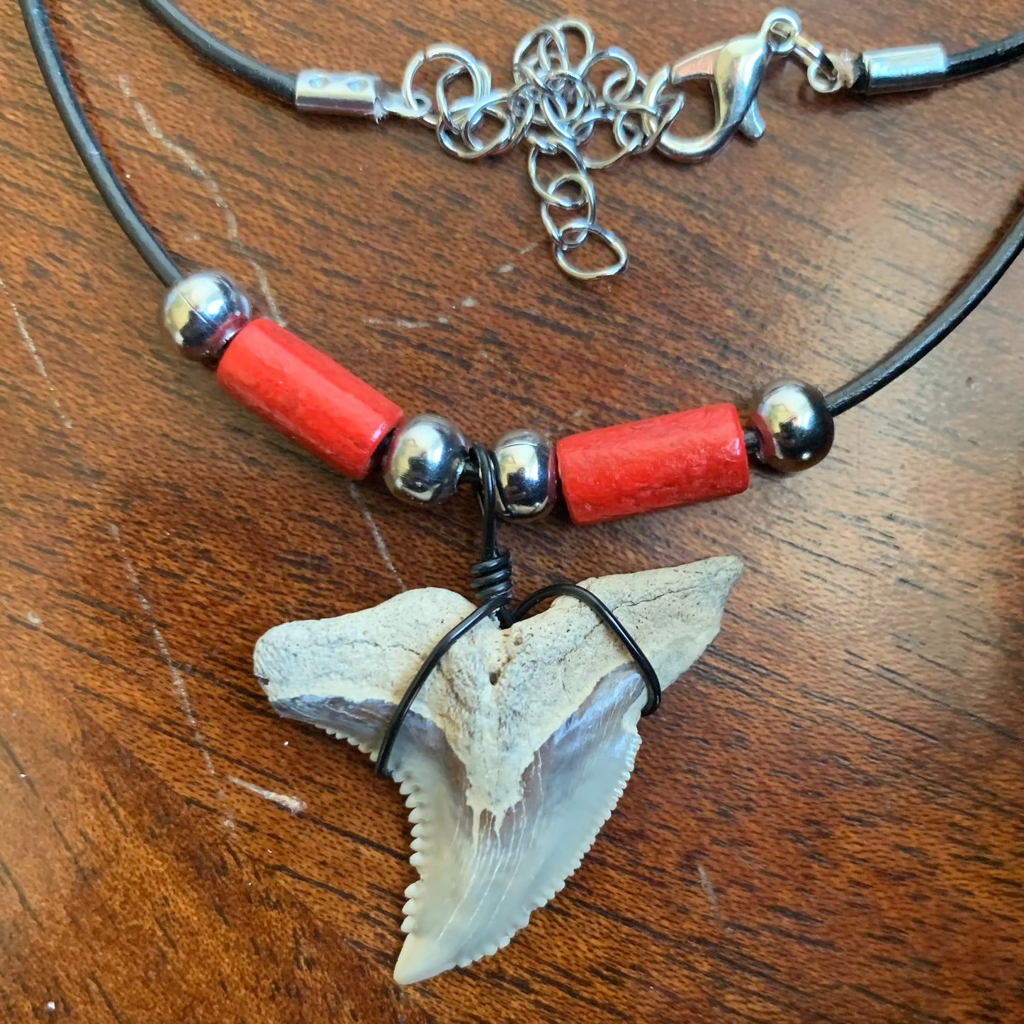 Real shark tooth necklace made from a fossil snaggle shark tooth pendant wrapped with black wire, hung on a black cotton cord with colorful beads