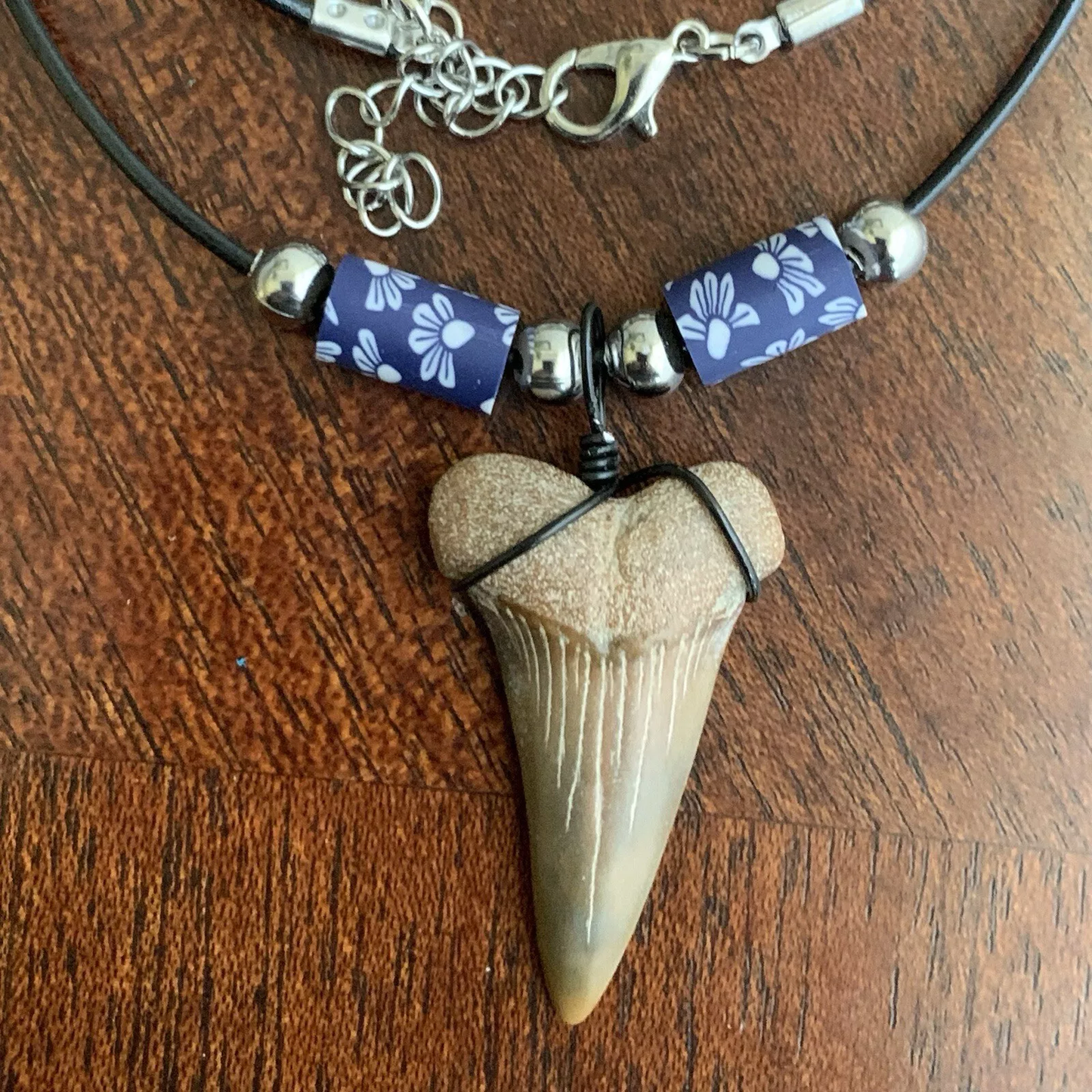 Real shark tooth necklace made from a fossil lesser white shark tooth pendant wrapped with black wire, hung on a black cotton cord with colorful beads