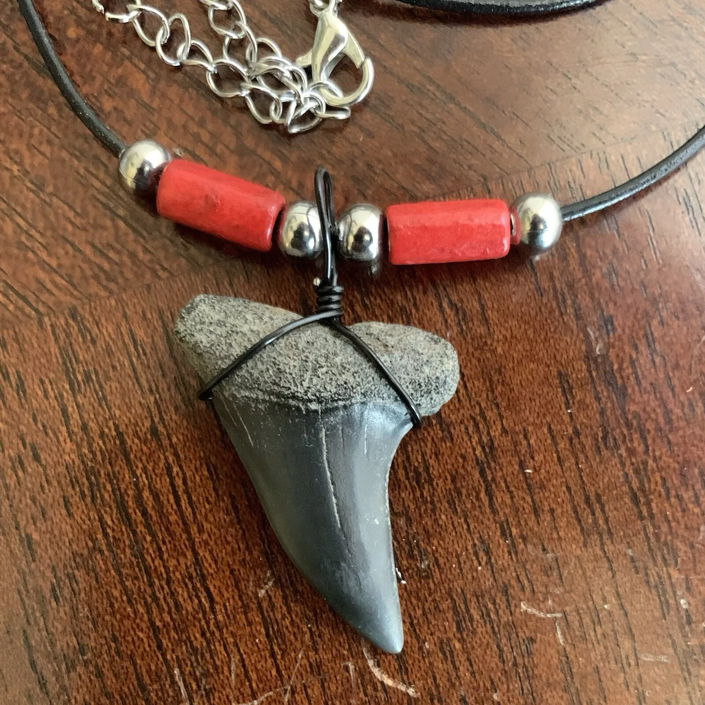 Real shark tooth necklace made from a fossil lesser white shark tooth pendant wrapped with black wire, hung on a black cotton cord with colorful beads