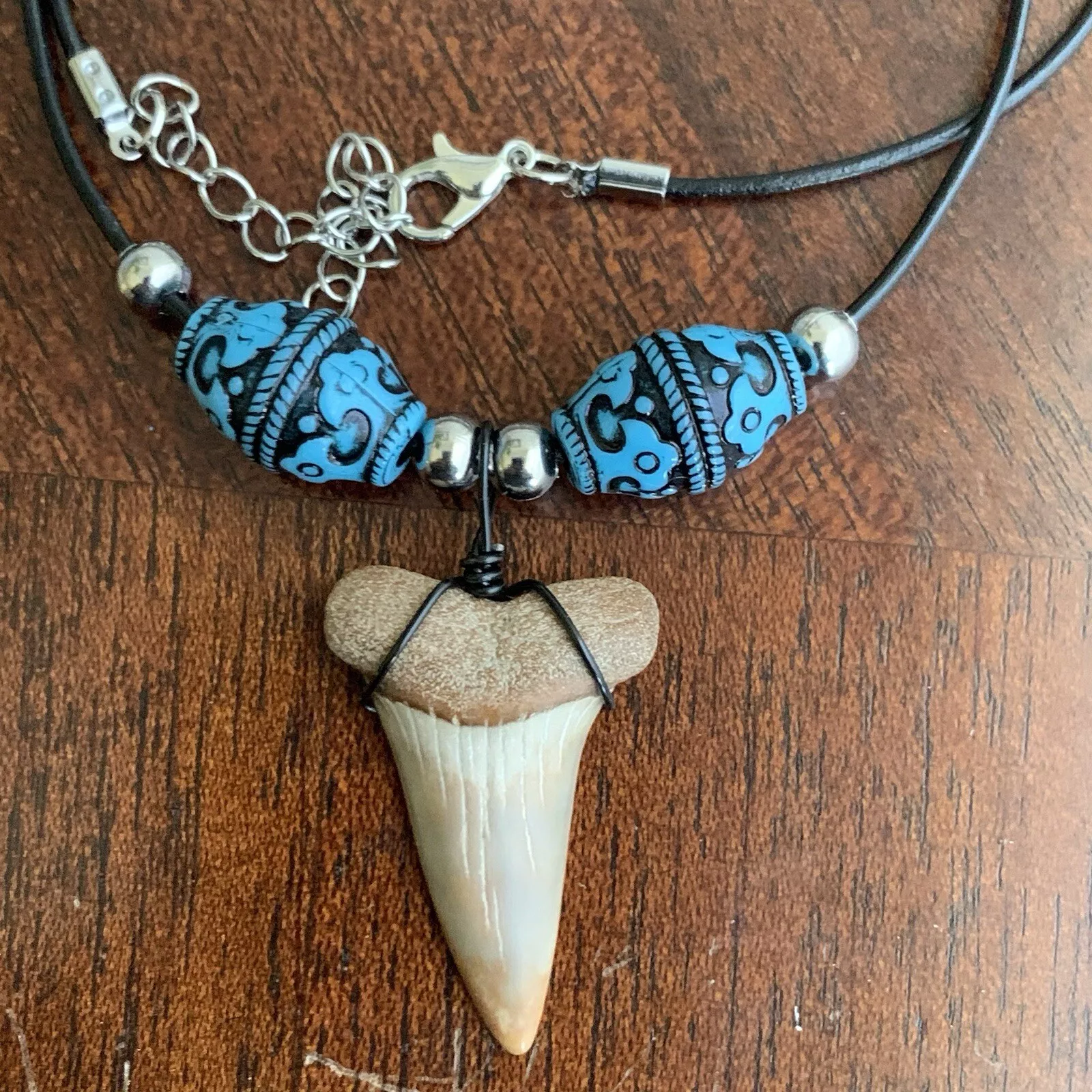 Real shark tooth necklace made from a fossil lesser white shark tooth pendant wrapped with black wire, hung on a black cotton cord with colorful beads