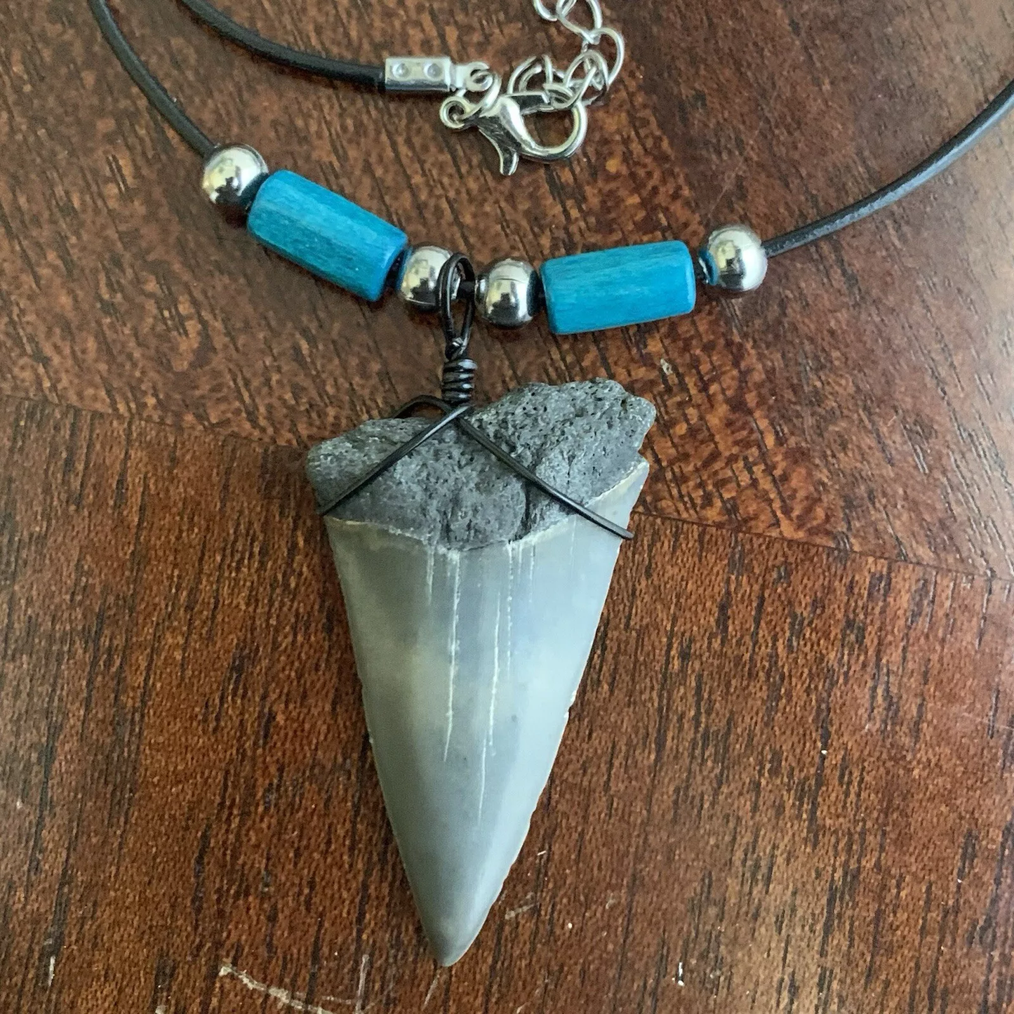 Real shark tooth necklace made from a fossil lesser white shark tooth pendant wrapped with black wire, hung on a black cotton cord with colorful beads