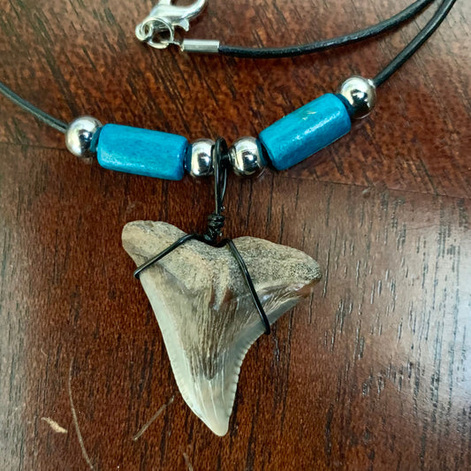 Real shark tooth necklace made from a fossil snaggle shark tooth pendant wrapped with black wire, hung on a black cotton cord with colorful beads