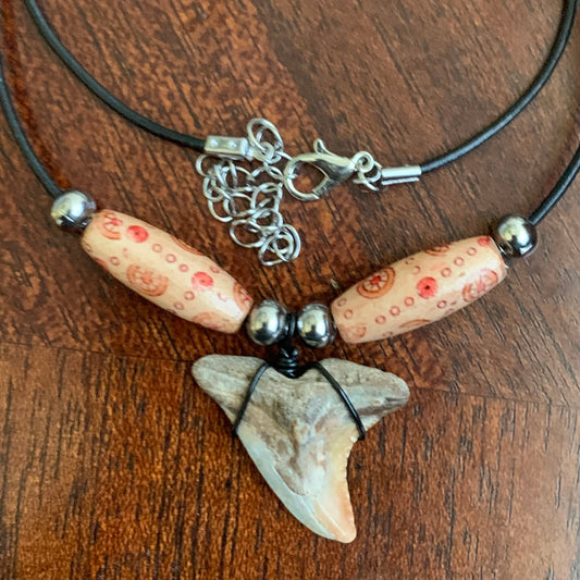 Real shark tooth necklace made from a fossil snaggle shark tooth pendant wrapped with black wire, hung on a black cotton cord with colorful beads