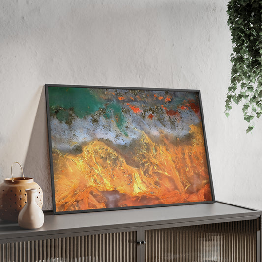 Wall art print capturing a captivating close-up photograph of a flame agate with its orange, white and green color. The picture is in a black frame and is leaning against the wall, on a low height cabinet, in the living room.