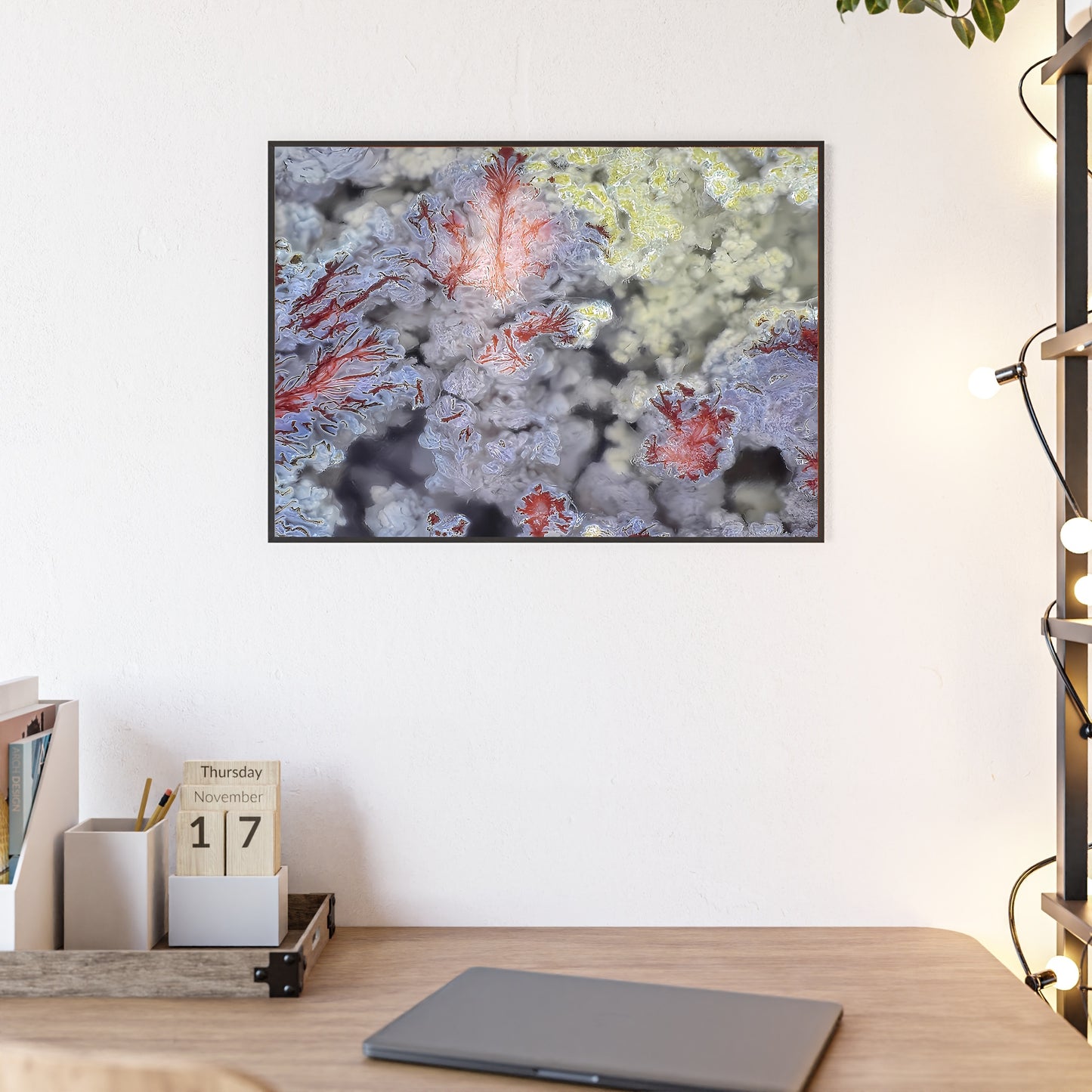 Rock art wall print featuring a scenic moss agate with its vibrant blue, red and yellow colors.  The picture is in a black frame hanging above a desk in the bedroom of a home.