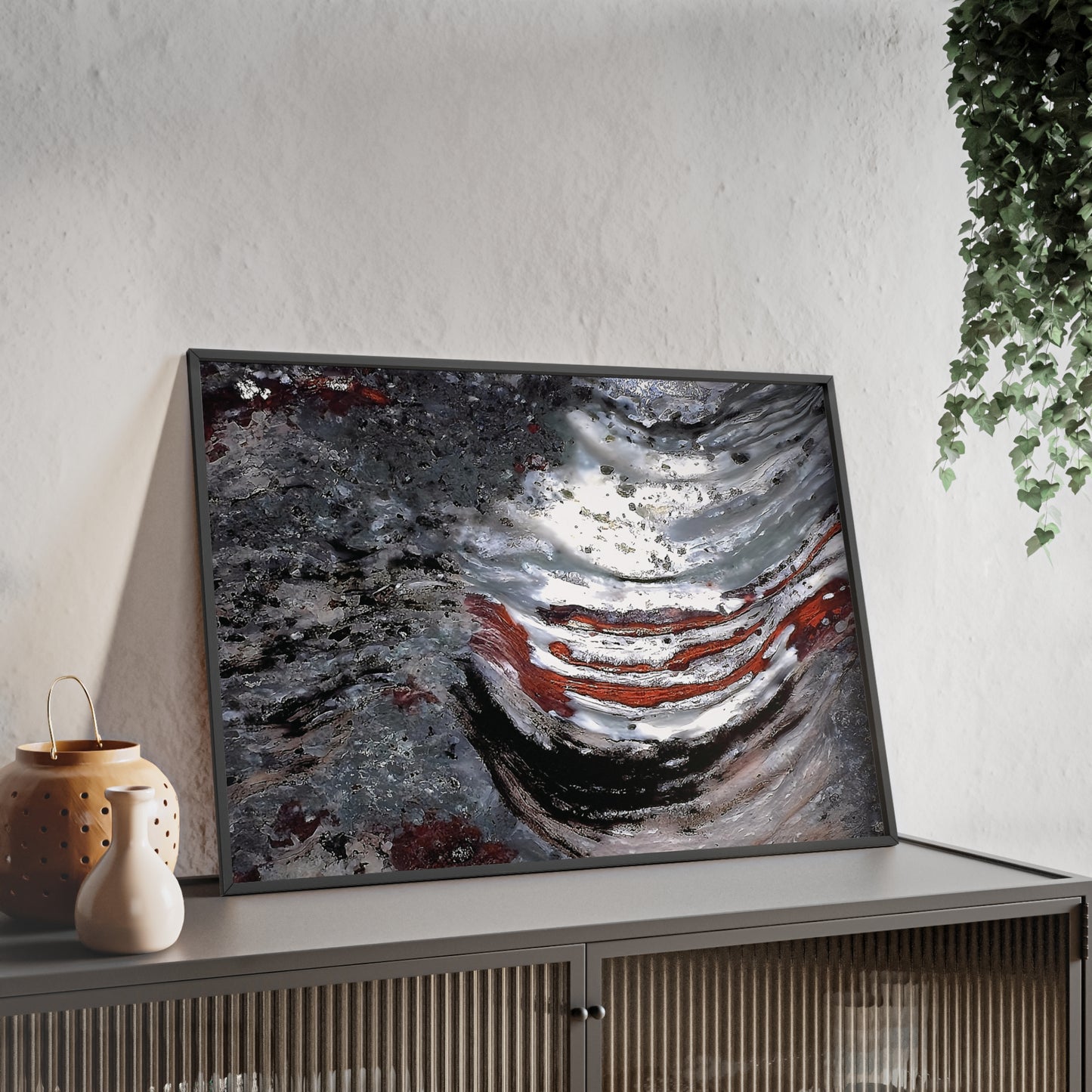 Wall art print capturing a captivating close-up photograph of the stromatolite Collenia undosa with its gray, red and white colors. The picture is in a black frame and is leaning against the wall, on a low height cabinet, in the living room.
