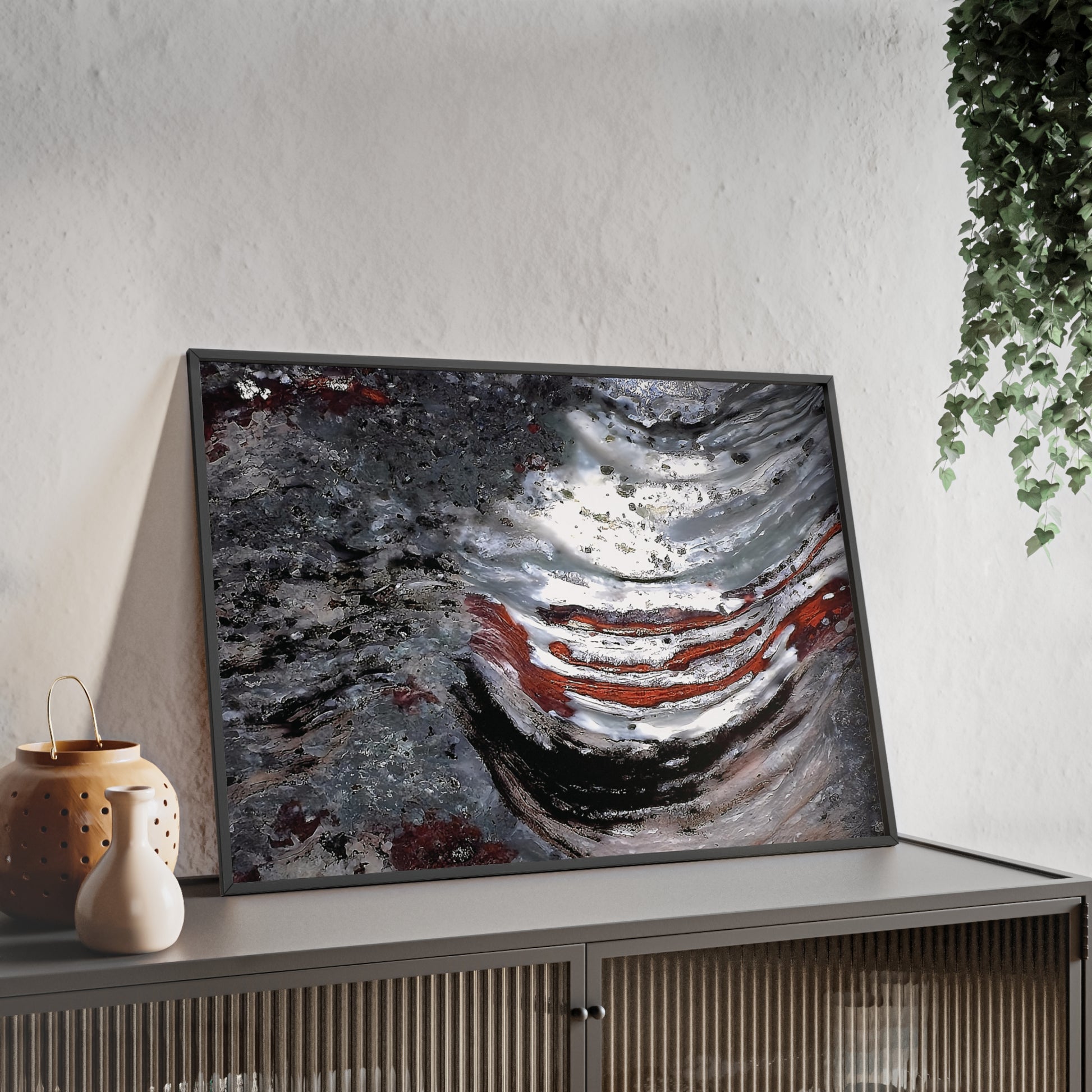 Wall art print capturing a captivating close-up photograph of the stromatolite Collenia undosa with its gray, red and white colors. The picture is in a black frame and is leaning against the wall, on a low height cabinet, in the living room.