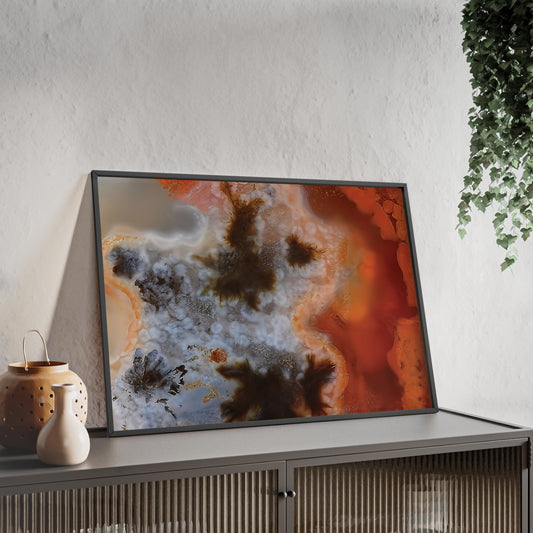 Wall art print capturing a captivating close-up photograph of a texas plume agate with its red white and brown colors. The picture is in a black frame and is leaning against the wall, on a low height cabinet, in the living room.