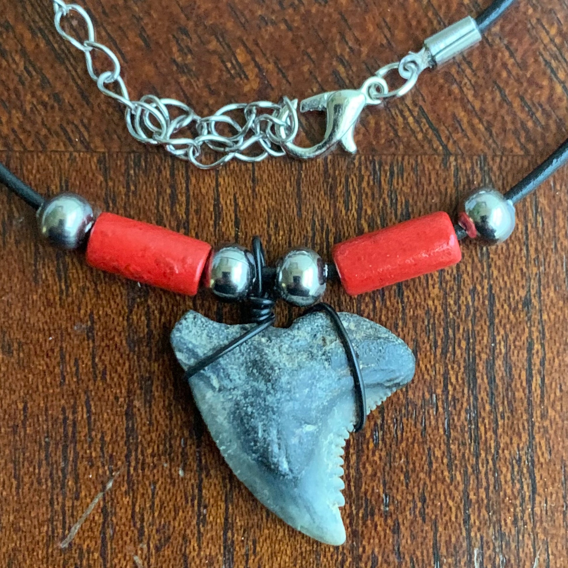 Real shark tooth necklace made from a fossil snaggle shark tooth pendant wrapped with black wire, hung on a black cotton cord with colorful beads