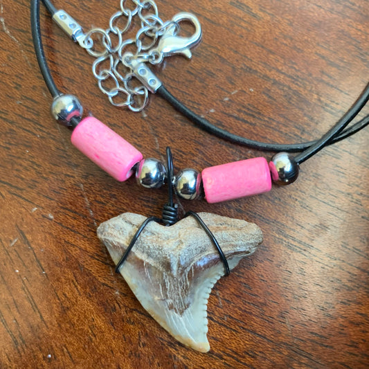 Real shark tooth necklace made from a fossil snaggle shark tooth pendant wrapped with black wire, hung on a black cotton cord with colorful beads